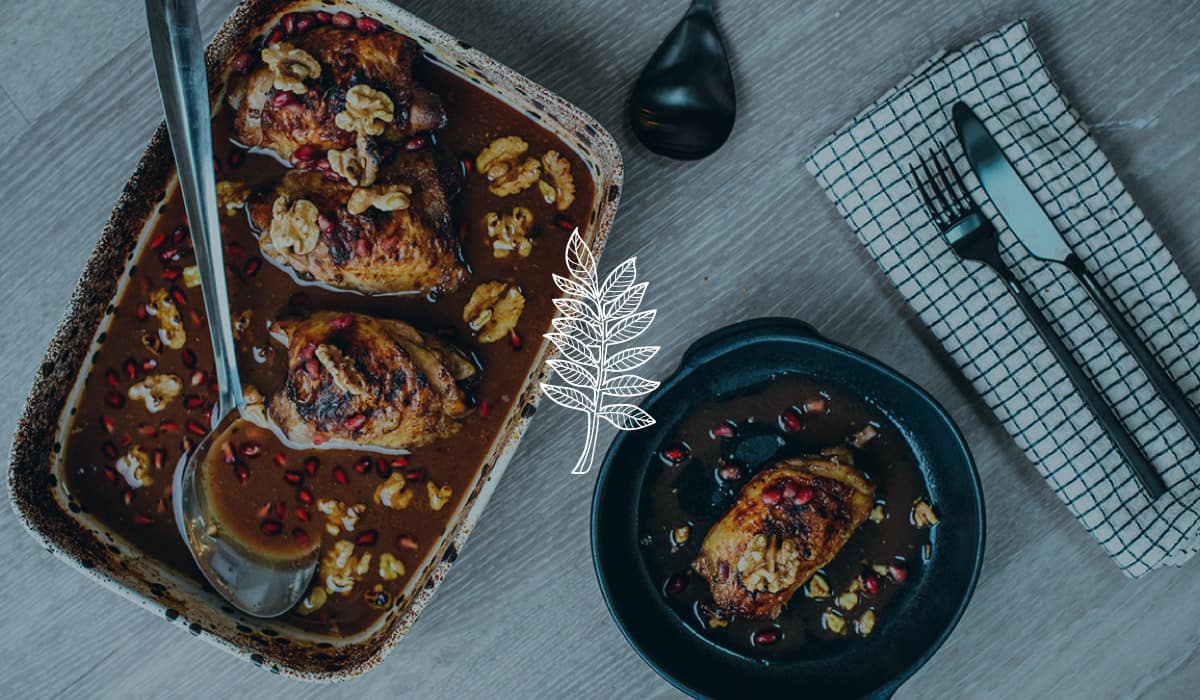 A shot of 2 chicken dishes from above and a napkin to the right with a knife and fork resting on it. A brand illustration of a liquorice leaf is laid across the image.