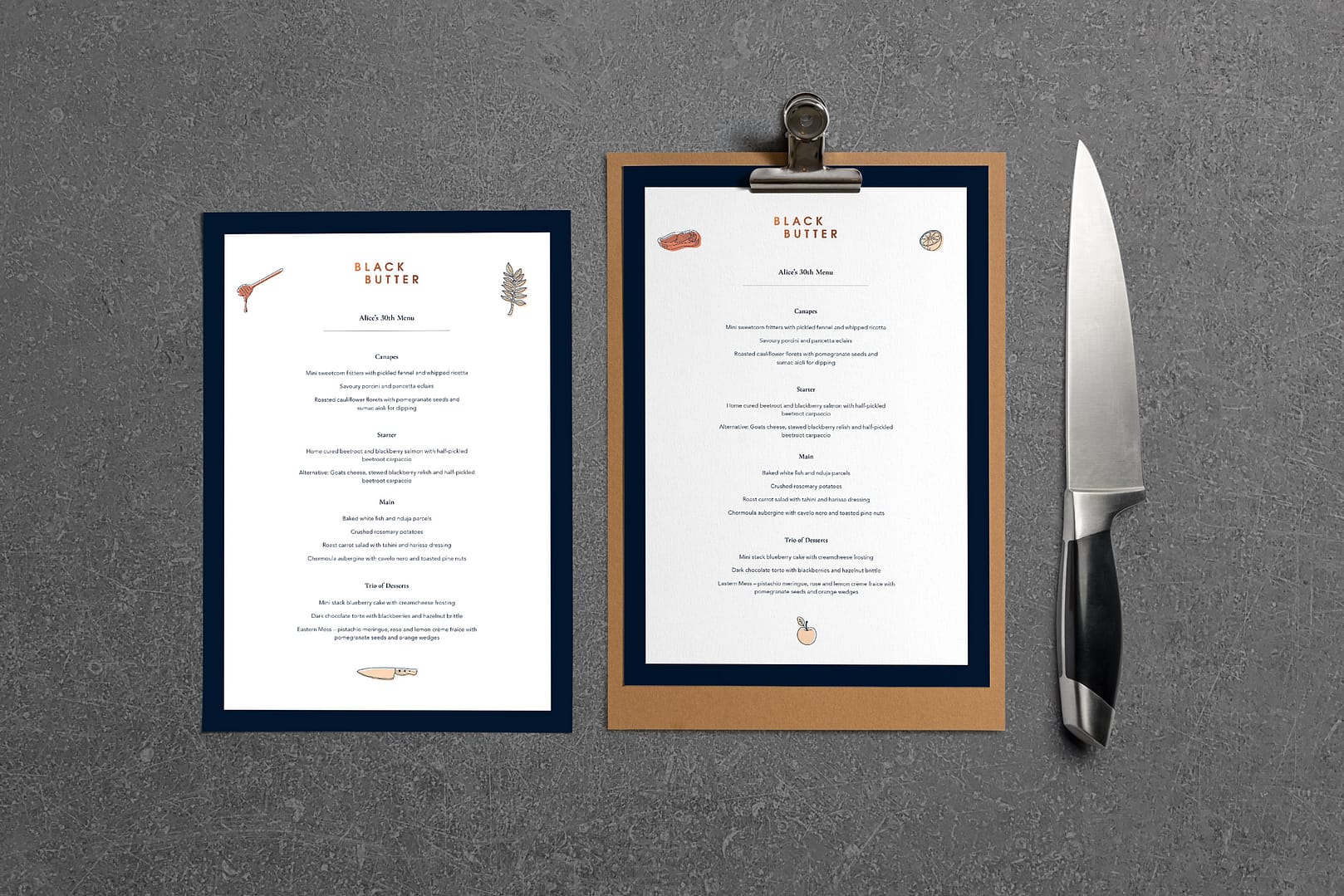 2 samples of Black Butter menus. One is on card and the other is on a clipboard. They are photographed from above on a concrete surface with a chef's knife to the right.