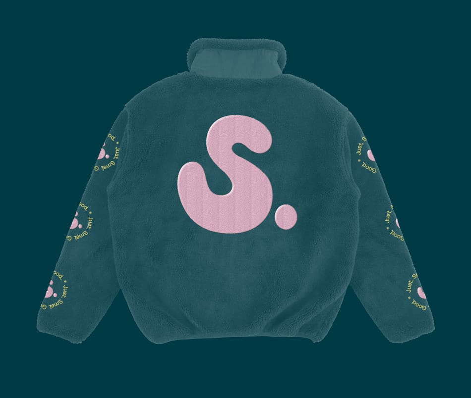 Back view of a SMEL fleece jacket on a dark background. The jacket is mainly black with a large pale pink "S." logo across the back. The sleeves continue the yellow "Just Smel. Good." circular pattern surrounding pink "S." logos.