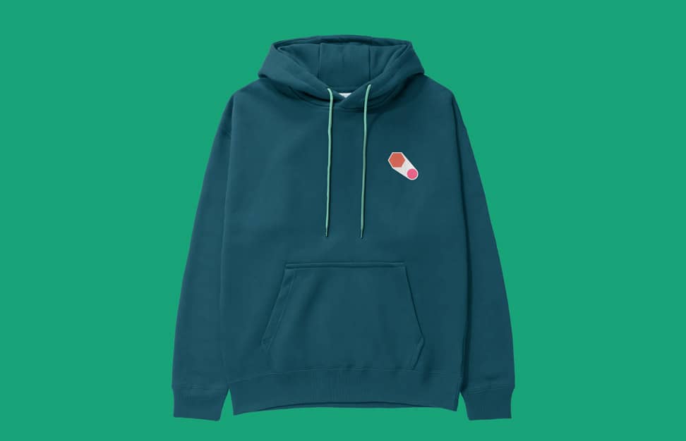 Teal hoodie with a small brand logo on the chest, displayed on a green background.